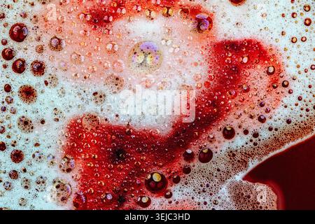 Detergent foam with bubbles and colored bubbles in red liquid Stock Photo