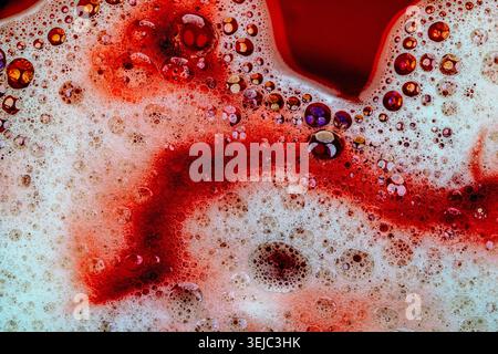 Detergent foam with bubbles and colored bubbles in red liquid Stock Photo