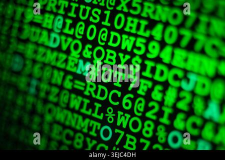 Glowing green computer code and hexadecimal numbers displayed on a dark screen with shallow depth of field Stock Photo
