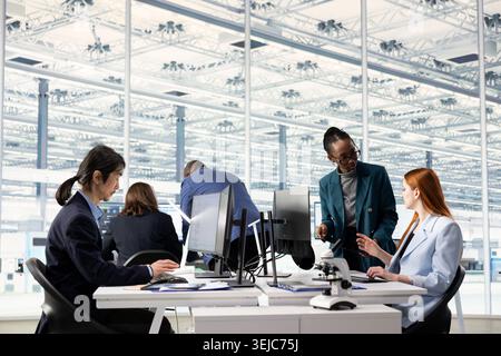 Diverse coworkers doing semiconductors hardware prototyping in office, brainstorming. Multiethnic engineering team collaborating on technical innovations in microchip factory RD lab Stock Photo