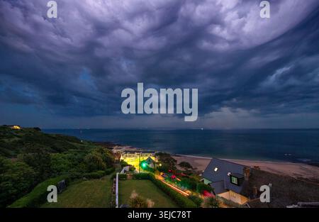 Sheet lightning through the heavy rain clouds above Langland Bay, Swansea tonight signalling an end to the extreme May heat. Stock Photo