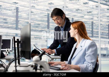 Hardware designer in microchip in manufacturing plant office using AI to upgrade microelectronics. Asian man in RD facility using neural network technology to improve semiconductors production Stock Photo