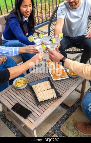 Happy friends toasting drinks celebrating together and enjoying snacks outdoors on a patio Stock Photo