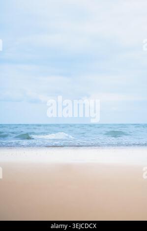 A calm, scenic view of the ocean shoreline under a soft, overcast sky. Stock Photo