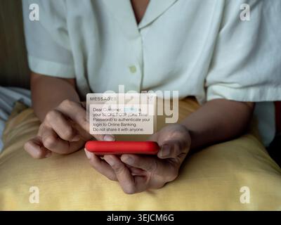 Woman receiving fake OTP message on smartphone during online banking login. Concept of cybersecurity, phishing scam, mobile banking fraud, identity th Stock Photo