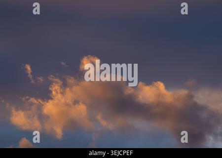 Golden-lit clouds against a deep blue sky at sunset Stock Photo