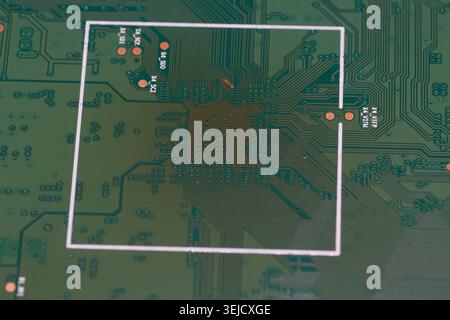 Macro photograph of a green printed circuit board (PCB), showing detailed copper traces, solder pads, and technical printed markings. Stock Photo