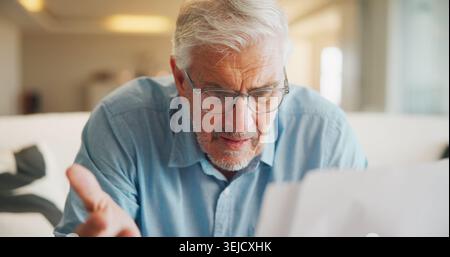 Documents, confused and old man in home with stress, angry or question for insurance on sofa. Shocked, frustrated and senior person reading paperwork Stock Photo