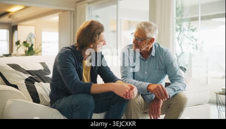 Love, home and senior dad with man for conversation, connection and bonding together on weekend. Elderly father, son or talking on sofa with parent Stock Photo