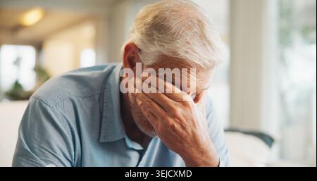 Upset, crying and senior man in home on weekend with loneliness, grief or mourning in living room. Emotion, sad and elderly male person with Stock Photo