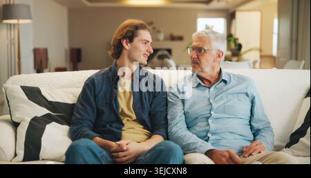 Love, home and senior father with man for conversation, connection and bonding together on weekend. Elderly dad, son or talking on sofa with parent Stock Photo