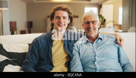 Senior father, son and portrait on sofa with love, hug and happy for bonding together in home. Family, relaxed and man with elderly dad for support Stock Photo