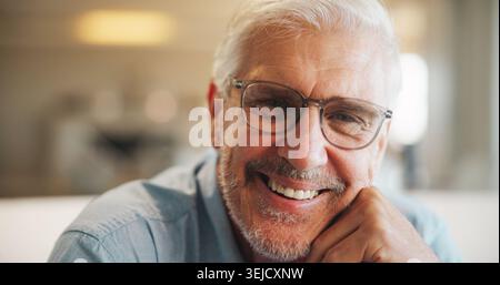Senior, man and happy portrait in home for comfortable retirement, peaceful morning and wellness. Pensioner, elderly person and relax in living room Stock Photo