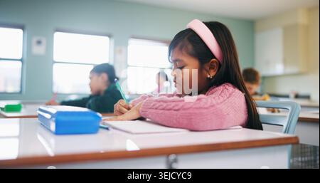 Writing, assessment and exam with kids in classroom for test, child development and knowledge. Education, notebook and lesson with students on school Stock Photo
