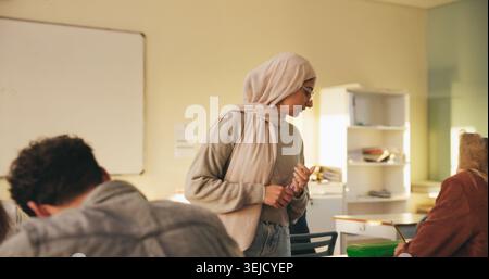 Teacher, muslim woman and students in class for exam, test supervision and course evaluation. Teaching, progress and islamic educator at high school Stock Photo