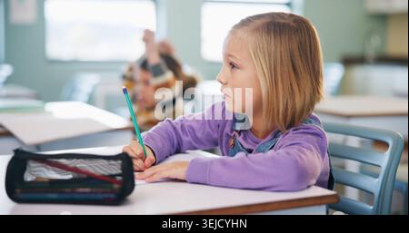 Writing, learning and exam with girl in classroom for test, child development and knowledge. Education, notebook and lesson with student on school Stock Photo