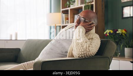 Tired, sleeping and senior man in living room with rest, glasses and peaceful retirement in nursing home. Elderly person, fatigue and relax on couch Stock Photo