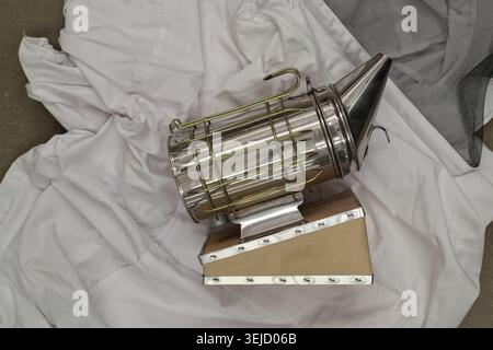 Beekeeping equipment smoker and protective suit agriculture flat lay. Stock Photo