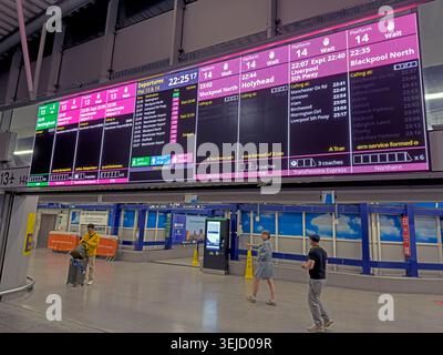 Passengers check digital screens delayed services at congested Manchester Piccadilly platforms 13 and 14, a notorious Castlefield Corridor bottleneck. Stock Photo