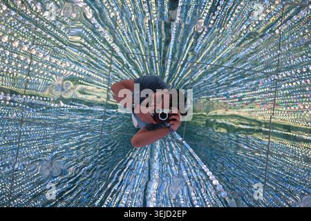 Photographer taking a self portrait reflection in a radial textured glass mirror creating a hypnotic and starburst light effect Stock Photo