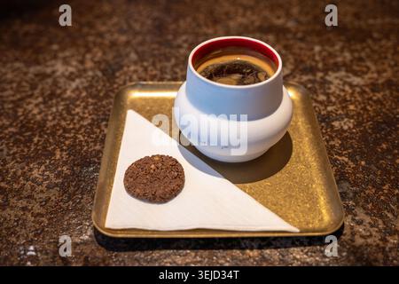 Hot Coffee in Ceramic Cup on Brass Tray with Chocolate Cookie and Napkin Stock Photo