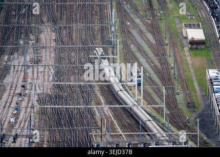 Close elevated view of an SNCF TGV train moving through electrified railway tracks and overhead lines in Paris, France. Stock Photo