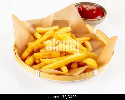 Crispy golden french fries in a paper-lined woven basket with a side of tomato ketchup. Minimalist studio shot with bright, even lighting on a clean w Stock Photo
