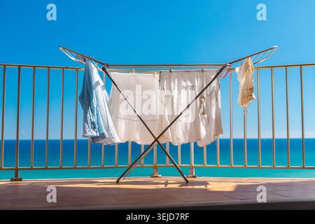 Laundry drying on balcony with turquoise sea view on sunny summer day at beach apartment near ocean coastline Stock Photo