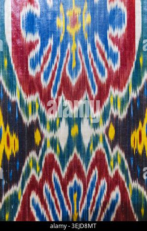 Vibrant handwoven ikat textile featuring bold geometric motifs in red, blue, yellow and green. Traditional patterned fabric evokes cultural heritage, Stock Photo