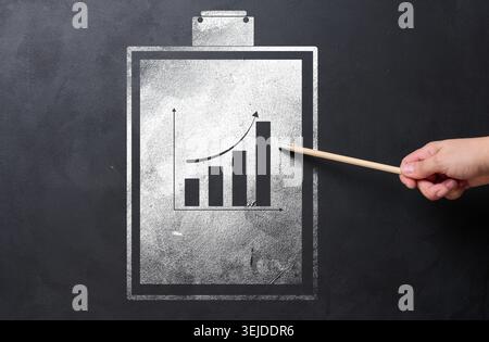 A folder holder for sheets of paper with a graph drawn with white chalk on a black chalk board Stock Photo