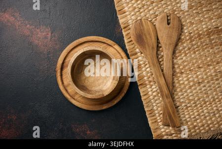 Empty wooden plate and wooden spoons on black background, top view Stock Photo