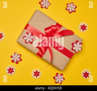 Christmas gift wrapped in red ribbon on yellow background Stock Photo