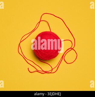 Ball of red woolen thread on yellow background, top view Stock Photo