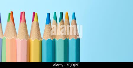 Multicolored wooden pencils sharpened on blue background, school supplies Stock Photo