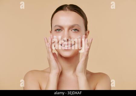 Portrait of Adult Woman Applying Moisturizer for Skincare Promotion Stock Photo