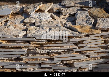 A detailed close-up view of a rustic stone wall constructed from irregularly shaped, flat pieces of natural rock, showcasing varied textures and earth Stock Photo