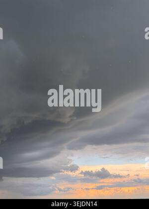 Rain falls from moody clouds at dusk Stock Photo