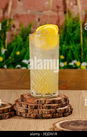Chilled citrus lemonade in a patterned glass on wood coasters Stock Photo