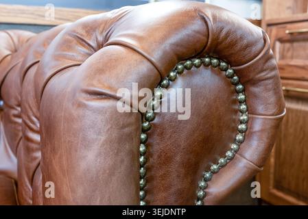 Brown leather sofa armrest with carriage tie and brass rivets Stock Photo