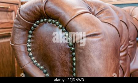 Brown leather sofa armrest with carriage tie and brass rivets Stock Photo