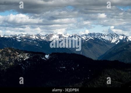Snow capped mountains under a dramatic cloudy sky Stock Photo