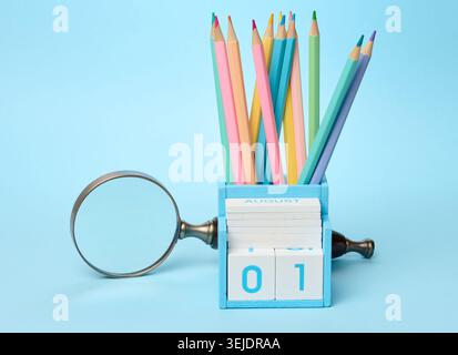 Multicolored wooden pencils sharpened in a glass on a blue background, school supplies Stock Photo