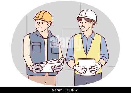 Two man builders in worker uniform look to side discussing construction process. Architects or engineers wearing protective helmets stand with papers Stock Photo