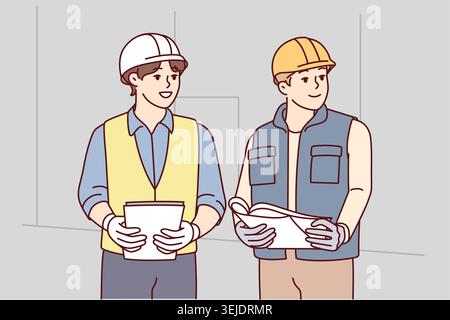 Two man builders in worker uniform look to side discussing construction process. Architects or engineers wearing protective helmets stand with papers Stock Photo