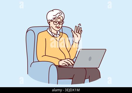 Elderly man makes video call through laptop sitting in chair and waving hand greeting interlocutor Stock Photo