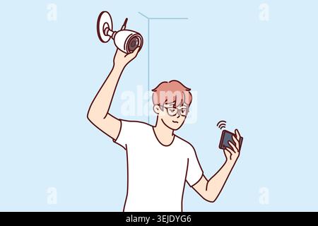 Man installs surveillance camera on wall and holds mobile phone, watching video through WIFI network Stock Photo