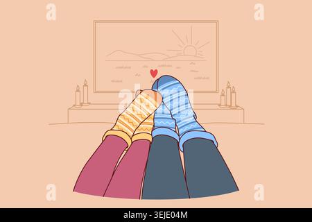 Feet of loving couple in autumn warm socks lying on sofa and watching TV in romantic home atmosphere Stock Photo