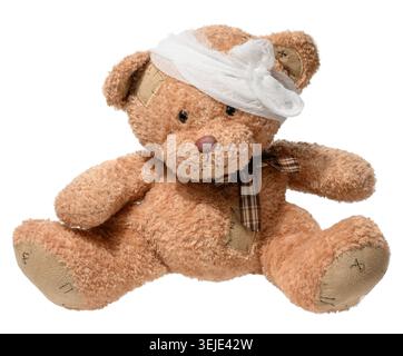 Soft brown teddy bear with stitched patches, head bandage, and plaid bow tie, isolated on white background. Symbol of care, chil Stock Photo