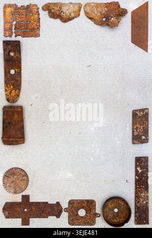A group of various old rusty bits and pieces arranged on a concrete surface. Old rusty nuts, bolts, nails and other parts flay lay on gray background. Stock Photo