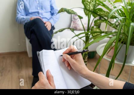 Close Up of Psychologist Hand Taking Notes During Therapy Session with Client Stock Photo